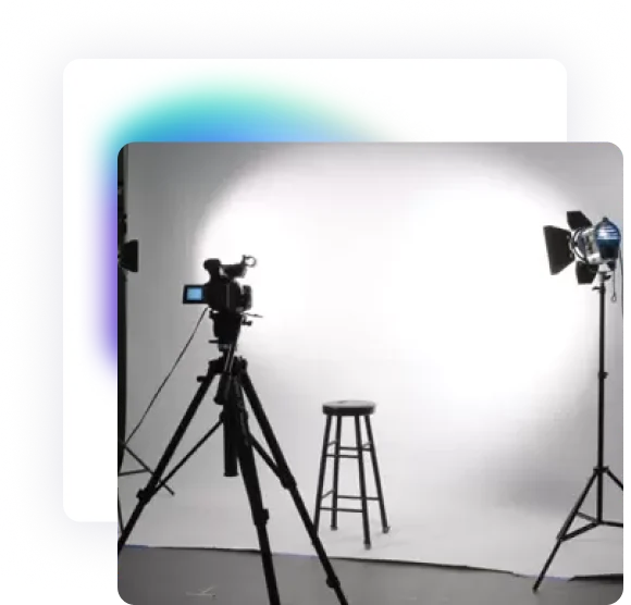 A studio with floor lighting and a camera mounted on a tripod facing the studio's white background kit.